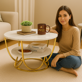 Woman sitting on the floor next to a small round table with decor items in a home setting.